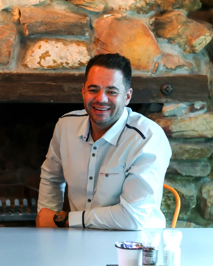Peter Groenenstein smiling, seated in front of a stone fireplace