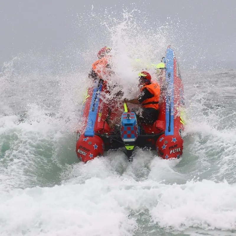 Red inflatable boat ploughing into a breaking wave